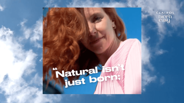 Redhead with the line Natural isn't just born against a blue sky